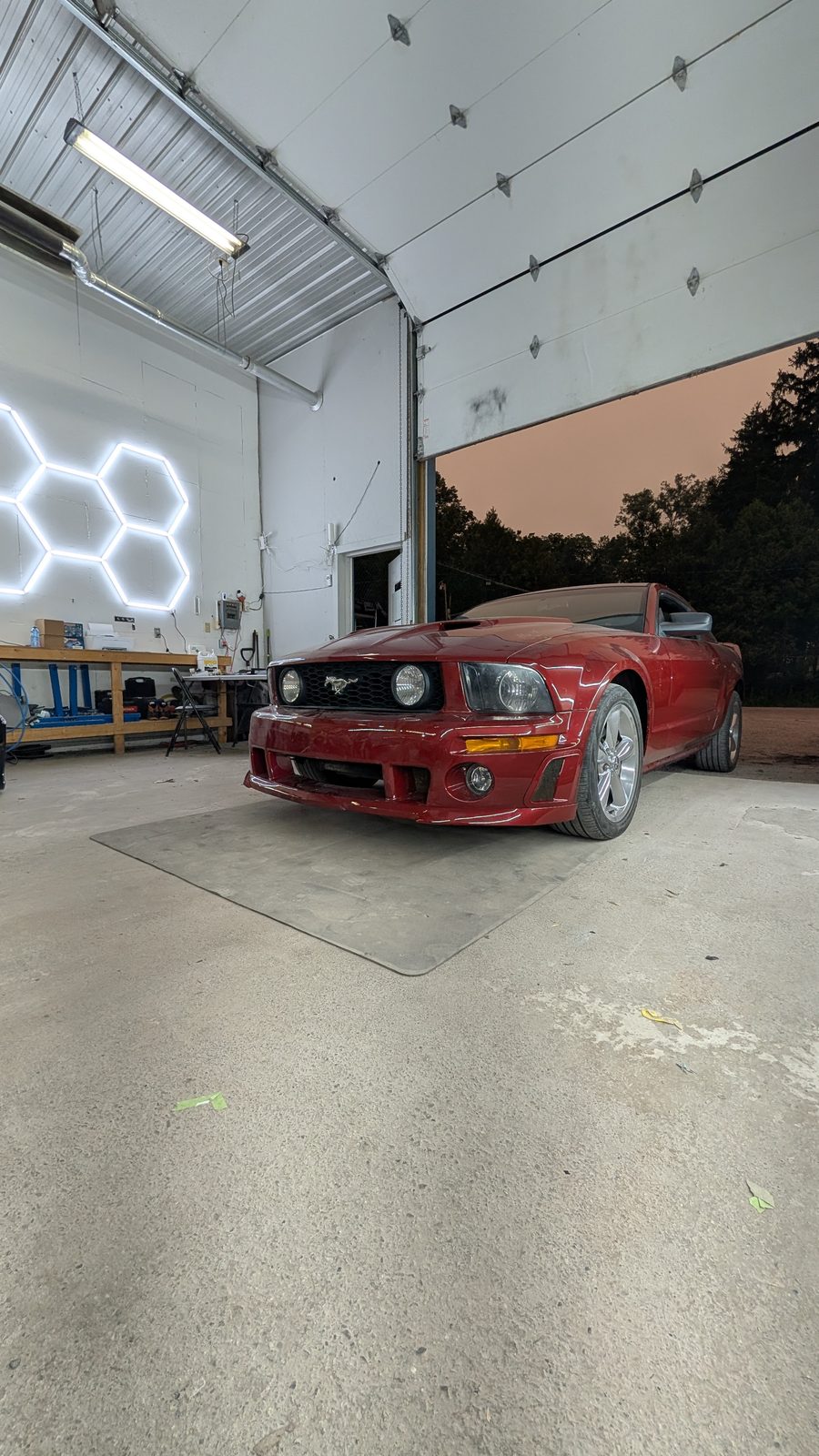 Red convertible detailed under The Hive's neon signage